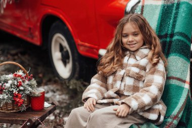 Noel 'i ve yeni yılı kutlayan bayan çocuk kış tatilini dışarıda kutluyor. Aktif küçük kız kozalaklı ormanda çocukluğunun tadını çıkarıyor.