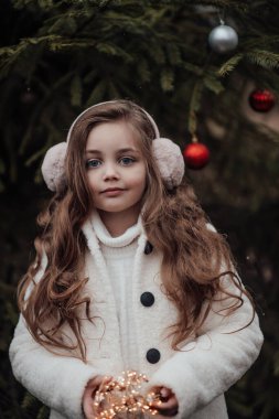 Aktif küçük kız ormanda istirahat edip çocukluk yılbaşı balolarının tadını çıkarıyor. Noel 'i ve yeni yılı kutlayan kadın çocuk kış tatilini dışarıda kutluyor.