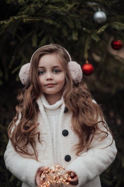 Aktif küçük kız ormanda istirahat edip çocukluk yılbaşı balolarının tadını çıkarıyor. Noel 'i ve yeni yılı kutlayan kadın çocuk kış tatilini dışarıda kutluyor.