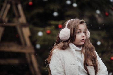 Aktif küçük kız ormanda istirahat edip çocukluk yılbaşı balolarının tadını çıkarıyor. Noel 'i ve yeni yılı kutlayan kadın çocuk kış tatilini dışarıda kutluyor.