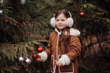 Aktif küçük kız ormanda istirahat edip çocukluk yılbaşı balolarının tadını çıkarıyor. Noel 'i ve yeni yılı kutlayan kadın çocuk kış tatilini dışarıda kutluyor.