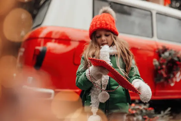クリスマスと新年の冬休みシーズンの屋外を祝う女性の子供 赤い封筒でサンタに手紙を保持し 奇跡を待っているオープンエアで楽しい時間を過ごす少女 — ストック写真