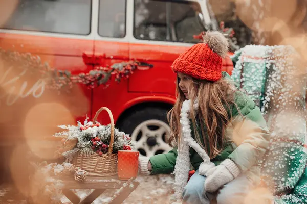 クリスマスと新年の冬休みシーズンの屋外を祝う女性の子供 赤い編まれた帽子の小さな女の子は Xmasバス近くの大きなマグカップからホットチョコレートを飲むオープンエアーで楽しい時間を過ごしました — ストック写真