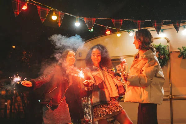 快乐的女孩们在户外庆祝圣诞节和新年假期 在旧式的圣诞预告片附近 活跃的年轻 多姿多彩的女性和快乐的女性朋友们 以及孟加拉的彩灯闪烁着快乐的光芒 — 图库照片