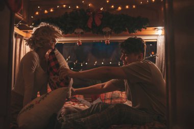 Noel 'i ve yeni yılı kutlayan mutlu çift kış tatili sezonunu karavanda kutluyor. Genç çift, Xmas karavanında yastık savaşı yaparak eğleniyor.