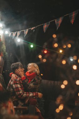 Noel 'i ve yeni yılı kutlayan mutlu çift, kış tatili sezonunu Camper Park' ta kutluyor. Genç çift dinleniyor ve rahatlıyor. Birlikte zaman geçiriyorlar. Xmas karavanı yakınında sarılıp öpüşüyorlar.