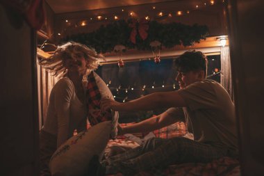 Noel 'i ve yeni yılı kutlayan mutlu çift kış tatili sezonunu karavanda kutluyor. Genç çift, Xmas karavanında yastık savaşı yaparak eğleniyor.
