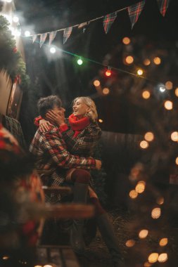 Noel 'i ve yeni yılı kutlayan mutlu çift, kış tatili sezonunu Camper Park' ta kutluyor. Genç çift dinleniyor ve rahatlıyor. Birlikte zaman geçiriyorlar. Xmas karavanı yakınında sarılıp öpüşüyorlar.