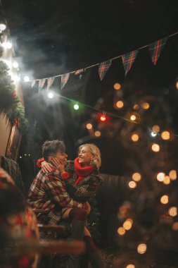 Noel 'i ve yeni yılı kutlayan mutlu çift, kış tatili sezonunu Camper Park' ta kutluyor. Genç çift dinleniyor ve rahatlıyor. Birlikte zaman geçiriyorlar. Xmas karavanı yakınında sarılıp öpüşüyorlar.