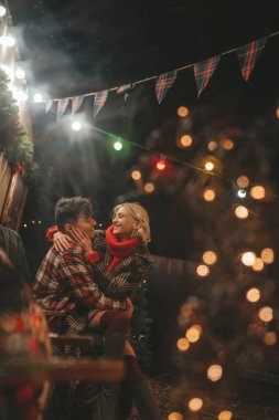 Noel 'i ve yeni yılı kutlayan mutlu çift, kış tatili sezonunu Camper Park' ta kutluyor. Genç çift dinleniyor ve rahatlıyor. Birlikte zaman geçiriyorlar. Xmas karavanı yakınında sarılıp öpüşüyorlar.