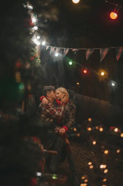 Noel 'i ve yeni yılı kutlayan mutlu çift, kış tatili sezonunu Camper Park' ta kutluyor. Genç çift dinleniyor ve rahatlıyor. Birlikte zaman geçiriyorlar. Xmas karavanı yakınında sarılıp öpüşüyorlar.