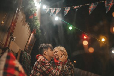 Noel 'i ve yeni yılı kutlayan mutlu çift, kış tatili sezonunu Camper Park' ta kutluyor. Genç çift dinleniyor ve rahatlıyor. Birlikte zaman geçiriyorlar. Xmas karavanı yakınında sarılıp öpüşüyorlar.