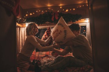 Noel 'i ve yeni yılı kutlayan mutlu çift kış tatili sezonunu karavanda kutluyor. Genç çift, Xmas karavanında yastık savaşı yaparak eğleniyor.