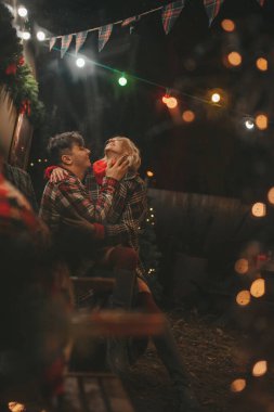 Noel 'i ve yeni yılı kutlayan mutlu çift, kış tatili sezonunu Camper Park' ta kutluyor. Genç çift dinleniyor ve rahatlıyor. Birlikte zaman geçiriyorlar. Xmas karavanı yakınında sarılıp öpüşüyorlar.