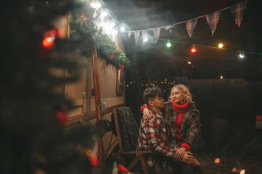 Noel 'i ve yeni yılı kutlayan mutlu çift, kış tatili sezonunu Camper Park' ta kutluyor. Genç çift dinleniyor ve rahatlıyor. Birlikte zaman geçiriyorlar. Xmas karavanı yakınında sarılıp öpüşüyorlar.