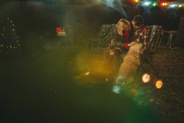 Noel 'i ve yeni yılı kutlayan mutlu çift, kış tatili sezonunu Camper Park' ta kutluyor. Genç mutlu çift, Xmas karavanı yakınında Golden Retriever köpeğiyle sarılıp vakit geçiriyorlar.