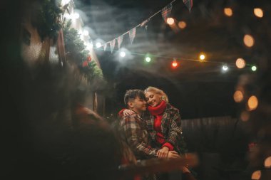 Noel 'i ve yeni yılı kutlayan mutlu çift, kış tatili sezonunu Camper Park' ta kutluyor. Genç çift dinleniyor ve rahatlıyor. Birlikte zaman geçiriyorlar. Xmas karavanı yakınında sarılıp öpüşüyorlar.