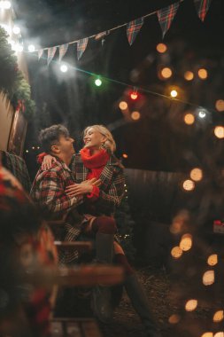 Noel 'i ve yeni yılı kutlayan mutlu çift, kış tatili sezonunu Camper Park' ta kutluyor. Genç çift dinleniyor ve rahatlıyor. Birlikte zaman geçiriyorlar. Xmas karavanı yakınında sarılıp öpüşüyorlar.