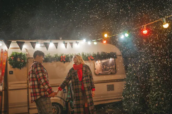 在坎普公园 一对欢欢喜喜的夫妇在庆祝圣诞节和新年假期 一对快乐的年轻夫妇在圣诞露营拖车旁的初雪中欢欢喜喜地拥抱和亲吻 — 图库照片