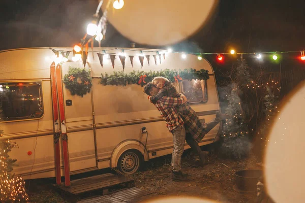 キャンパーパークでクリスマスと新年の冬の休暇シーズンを祝うハッピーカップル 若いカップル休憩とリラクゼーション時間を一緒に過ごすXmasキャンピングカーのトレーラーの近くで抱擁とキス — ストック写真