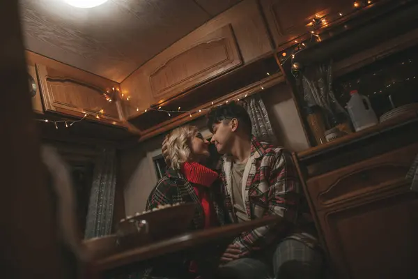 Happy couple celebrating Christmas and New Year winter holidays season in Camper Park. Young couple spending time together take selfie photo for social media in Xmas camper trailer