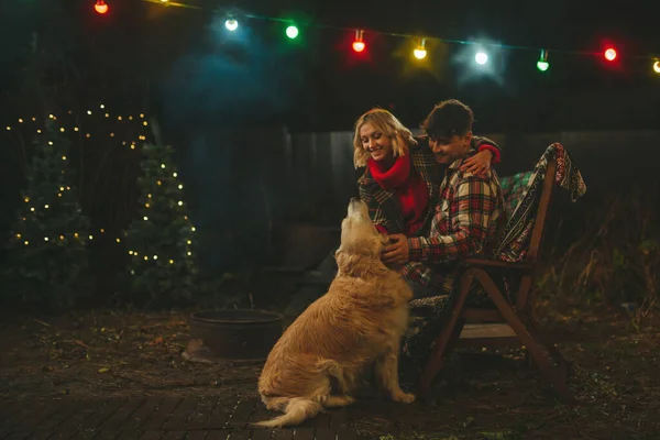 Noel 'i ve yeni yılı kutlayan mutlu çift, kış tatili sezonunu Camper Park' ta kutluyor. Genç mutlu çift, Xmas karavanı yakınında Golden Retriever köpeğiyle sarılıp vakit geçiriyorlar.