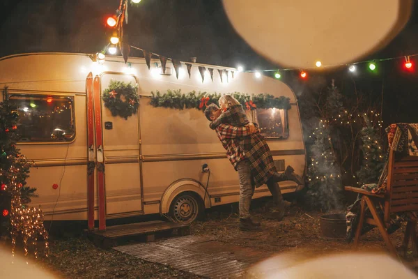 キャンパーパークでクリスマスと新年の冬の休暇シーズンを祝うハッピーカップル 若いカップル休憩とリラクゼーション時間を一緒に過ごすXmasキャンピングカーのトレーラーの近くで抱擁とキス — ストック写真