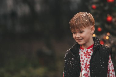 Küçük çocuk Noel 'i ve yeni yılı dışarıda kutluyor Noel Baba' yı Noel karavanın yanında bekliyor ve çocukluğun tadını çıkarıyor.