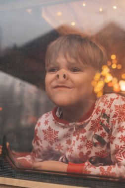Küçük çocuk Noel 'i ve yeni yıl tatilini kutlarken yüzünü buruşturuyor Noel Baba' yı Noel kampı karavanında bekliyor.
