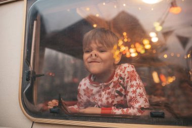 Küçük çocuk Noel 'i ve yeni yıl tatilini kutlarken yüzünü buruşturuyor Noel Baba' yı Noel kampı karavanında bekliyor.