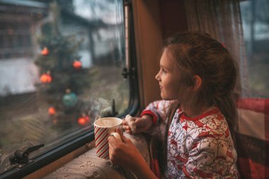 Küçük kız Noel 'i ve yeni yılı kutlarken süt içer ve Noel Baba' yı Noel kampı karavanında bekler.