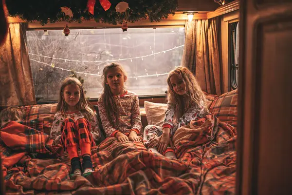 キャンパーでクリスマスと新年の冬の休暇シーズンを祝う子供たち 小さな女の子は子供の頃を楽しんでいるXmasキャンパーのトレーラーで耳元で秘密をささやく笑顔の時間を一緒に過ごします — ストック写真