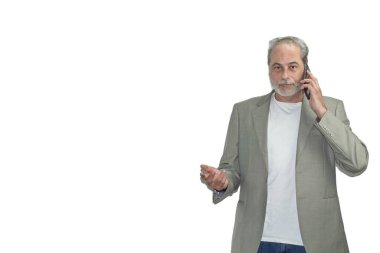 Sakallı olgun bir adam beyaz arka planda telefonla konuşuyor.