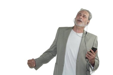 Kulaklık takan ve beyaz arka planda dans eden olgun bir adam.