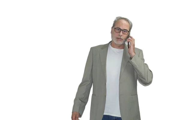 Sakallı ve gözlüklü olgun bir adam beyaz arka planda telefonla konuşuyor.