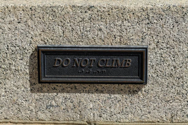 Do not climb, the metal sign on a granite wall. High-quality photo
