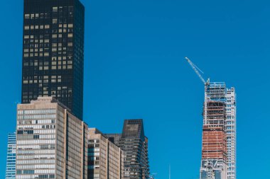 Bina, Crane ile birlikte, New York 'ta mavi gökyüzü arka planındaki bir binada yapım aşamasında. Yüksek kaliteli fotoğraf.