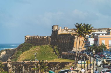  San Juan, Porto Riko 29 Mart 2021 - Güzel bir günde arka planda renkli binalar ve San Cristobal Kalesi olan caddeler arabalarla doludur.