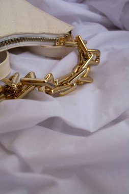 This eye-catching stock photo features a stylish black leather bag adorned with a large, shiny gold chain. The bag exudes a sense of luxury and sophistication, making it the perfect accessory for any fashion-forward individual. 