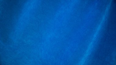 Arka plan olarak mavi kadife kumaş dokusu kullanılıyor. Yumuşak ve pürüzsüz tekstil malzemelerinin boş mavi kumaş arka planı. Metin için boşluk var.