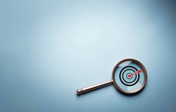 stock image Target board inside of magnifier glass for focus business objective target search concept and success on blue background and copy space.