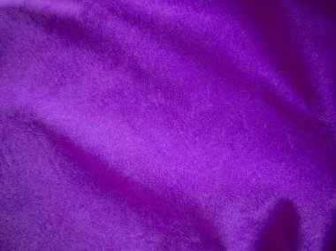 Arka plan olarak kullanılan mor kadife kumaş dokusu. Yumuşak ve pürüzsüz tekstil malzemelerinin lükslü mor kumaş arka planı. Metin için boşluk var.