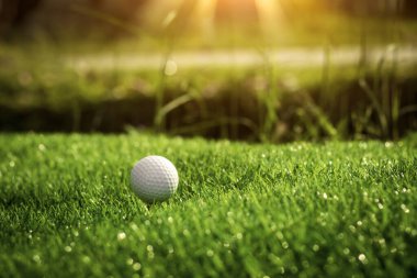 Golf ball close up on tee grass on blurred beautiful landscape of golf background. Concept international sport that rely on precision skills for health relaxation.	