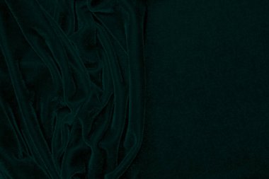 Arka plan olarak kullanılan koyu yeşil kadife kumaş dokusu. Yumuşak ve pürüzsüz tekstil malzemelerinin zümrüt renkli kumaş arka planı. Ezilmiş kadife. İpek için lüks zümrüt rengi.