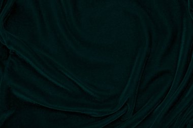 Arka plan olarak kullanılan koyu yeşil kadife kumaş dokusu. Yumuşak ve pürüzsüz tekstil malzemelerinin zümrüt renkli kumaş arka planı. Ezilmiş kadife. İpek için lüks zümrüt rengi.