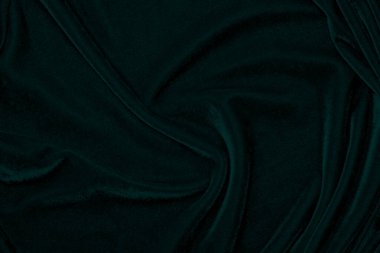 Arka plan olarak kullanılan koyu yeşil kadife kumaş dokusu. Yumuşak ve pürüzsüz tekstil malzemelerinin zümrüt renkli kumaş arka planı. Ezilmiş kadife. İpek için lüks zümrüt rengi.