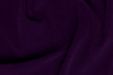 Arka plan olarak kullanılan koyu mor kadife kumaş dokusu. Yumuşak ve pürüzsüz tekstil malzemesinin mor renkli kumaş arka planı. Ezilmiş kadife. İpek için lüks koyu renk..