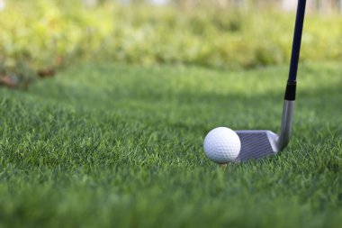 Golf topu golf arka planının bulanık güzellikteki golf sahasında çimlere yakın duruyor. Sağlık gevşemesi için hassas becerilere dayanan uluslararası spor kavramını kabul edin