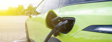 Şarj istasyonunda şarj edilen bir elektrikli araba. Şarj portu ve kablo, temiz enerji, sürdürülebilirlik ve modern ulaşım teknolojisi kavramını vurguluyor