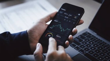 Yatırımcılar veri borsası indeksini akıllı telefon ekranı üzerinden analiz ederek yatırımların planlanması için borsa şemasını takas ederler. Kar, borsa ve kripto para birimi verileri, finansal.